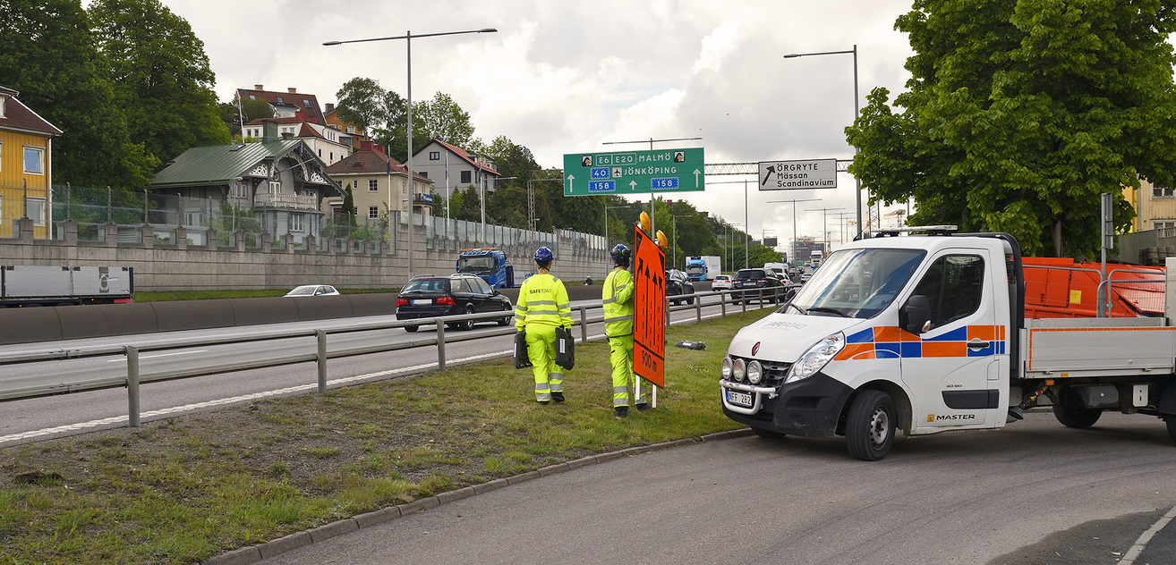 Två av Saferoads medarbetare ställer ut skylt vid väg i Göteborg