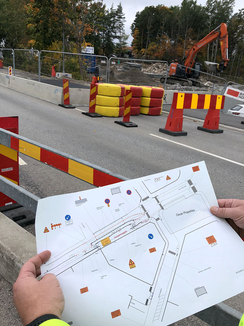Medarbetare håller i en utskrift av en TA-plan vid ett vägarbete i Stockholm